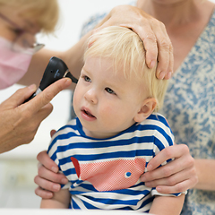 Image showing Infant baby boy child being examined by his pediatrician doctor during a standard medical checkup in presence and comfort of his mother. National public health and childs care care koncept.