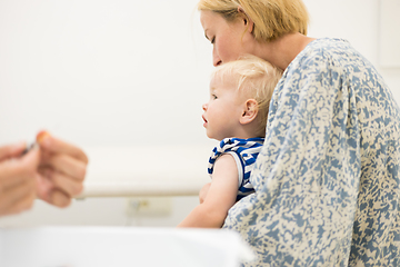 Image showing Child beeing vaccinated by pediatrician in presence of his mother. Preventive vaccination against Diphtheria, whooping cough, tetanus, hepatitis, haemophilus influenzae, pneumococcus, poliomyelitis