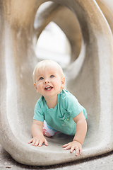 Image showing Child playing on outdoor playground. Toddler plays on school or kindergarten yard. Active kid on stone sculpured slide. Healthy summer activity for children. Little boy climbing outdoors.