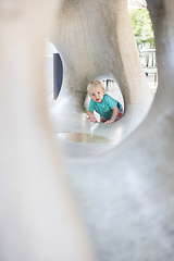 Image showing Child playing on outdoor playground. Toddler plays on school or kindergarten yard. Active kid on stone sculpured slide. Healthy summer activity for children. Little boy climbing outdoors.