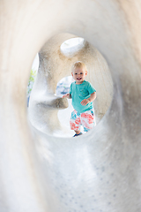 Image showing Child playing on outdoor playground. Toddler plays on school or kindergarten yard. Active kid on stone sculpured slide. Healthy summer activity for children. Little boy climbing outdoors.