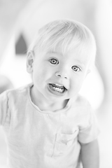 Image showing Black and white portrait of cute little infant baby boy child playing on outdoor playground. Toddler plays on school or kindergarten yard.