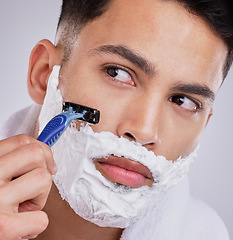 Image showing Beard, shaving and foam with man and razor in studio for hair removal, grooming and skincare. Cosmetics, self care and morning with face of model on gray background for cleaning and shaver product