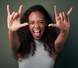 Image showing Woman, portrait and rock hand in green studio background shows tongue with emoji and crazy. Female person, rocker and gesture with hands to celebrate or winning with excited face for a party.