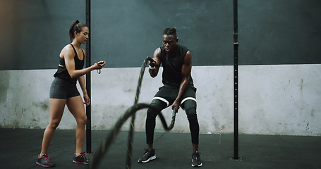 Image showing Battle rope, exercise and man with personal trainer and stopwatch at gym for training goals on wall background. Heavy, full body and male with coach at sports center for power, workout or resilience