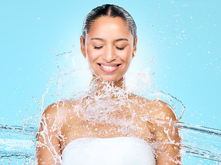 Image showing Water, splash and shower with woman in studio for hygiene, beauty and skincare. Wellness, cleaning and fresh with face of female model on blue background for spa, cosmetics and liquid mockup space