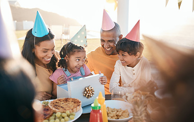 Image showing Birthday, party and family outdoors for celebration, bonding and present, happy and excited. Parents, children and gift for girl child at special event, smile and celebrating with food at restaurant