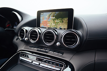 Image showing View from inside a car on a part of dashboard with a navigation unit and blurred street in front of a car