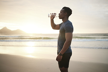 Image showing Fitness, beach and black man drinking water at sunset on running break, exercise or mockup. Drink, liquid and African male athlete with bottle for nutrition, hydration or health, wellness and ocean.