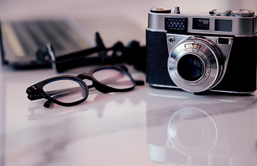 Image showing Closeup, desk and photography studio with camera, glasses and computer for art, journalist or news company. Retro equipment, spectacles and professional lens with laptop in office for newspaper job