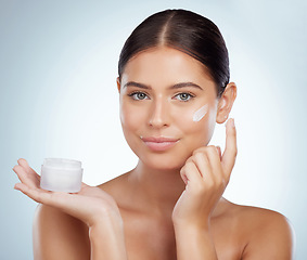Image showing Face, skincare and woman with cream container in studio isolated on a white background. Portrait, dermatology lotion and female model apply cosmetics, sunscreen or moisturizer product for skin health