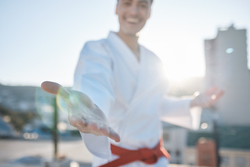 Image showing Karate, hand and fighting with a sports man in gi, training in the city on a blurred background. Exercise, gesture or virtue with a happy male athlete during a self defense workout for health closeup