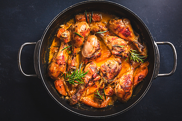 Image showing Baked chicken drumsticks with vegetables, casserole dish on black background