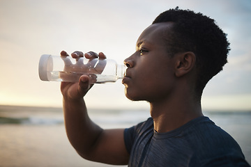 Image showing Black man, beach fitness and drinking water at sunset on running break, exercise or workout. Drink, liquid and African male athlete with bottle for nutrition, hydration or health, wellness and ocean.