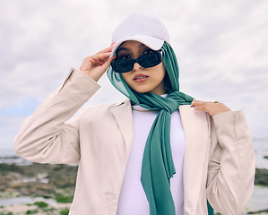 Image showing Portrait, fashion or sunglasses with an islamic woman outdoor in a cap and scarf for contemporary style. Muslim, faith or hijab for religion with a trendy young arab person outside in modern clothes