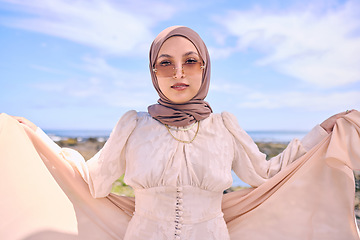 Image showing Portrait, fashion or religion with an arab woman outdoor in sunglasses and a scarf for contemporary style. Muslim, faith and dress with a trendy young islamic person posing outside in modern clothes