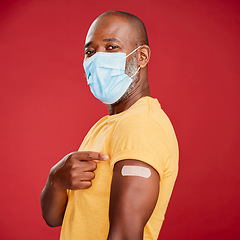 Image showing African man, covid and vaccine in studio portrait with pride, healthcare and wellness by red background. Black male model, face mask and point at arm with plaster, medicine and safety to stop virus