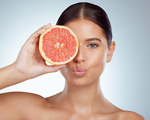 Image showing Face kiss, skincare and woman with grapefruit in studio isolated on white background. Portrait, natural or female model with fruit for vitamin c, nutrition or healthy diet, wellness or cosmetics pout