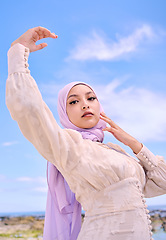 Image showing Portrait, fashion or faith with a muslim woman on a blue sky background in a scarf for modern style. Islam, religion and hijab with a trendy young arab person posing outside in contemporary clothes