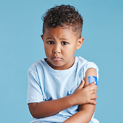 Image showing Portrait, sad and kid with arm bandage in studio isolated on a blue background. Face, upset and child with plaster after vaccine, injury or wound for healthcare wellness, first aid or medical help.