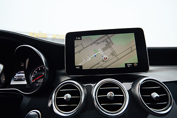 Image showing View from inside a car on a part of dashboard with a navigation unit and blurred street in front of a car