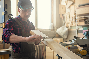 Image showing The worker makes measurements of a wooden board