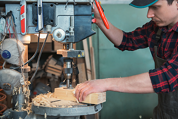 Image showing Carpenters with electric drill machine drilling wooden board