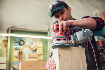 Image showing Worker grinds the wood box