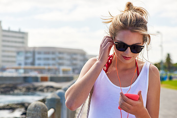 Image showing Travel, woman with smartphone and earphones in city street listening to music. Traveling, technology and female person online streaming podcast or radio outside in urban a road with cellphone