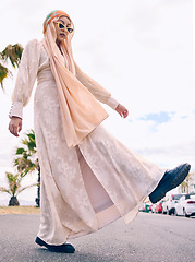 Image showing Woman, muslim fashion and street in low angle portrait with gen z aesthetic, beauty and walking in city. Young islamic girl, student and clothes with sunglasses, freedom and travel on road in Dubai