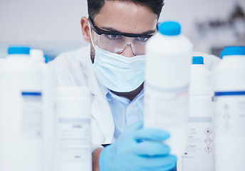 Image showing Stock check, chemical bottle and man scientist with mask at pharmaceutical lab working. Research, container label reading and science of a male worker with manufacturing job and chemistry inventory