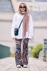 Image showing Portrait, fashion or faith with an islamic woman outdoor in a cap and scarf for contemporary style. Islam, faith and hijab with a full length trendy young muslim person outside in modern clothes