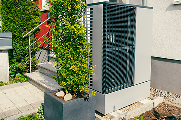 Image showing Modern air source heat pump installed outside of new city house