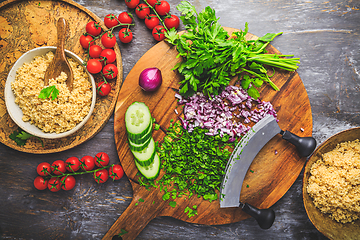 Image showing Preparing traditional oriental salad Tabouleh with couscous or bulgur, ingredients on cutting board