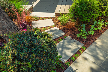 Image showing Detail of  garden path with stone slabs with bark mulch and native plants. Landscaping and gardening concept.