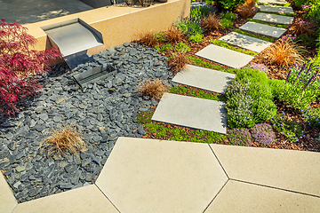 Image showing Detail of  garden path with stone slabs with bark mulch and native plants. Landscaping and gardening concept.