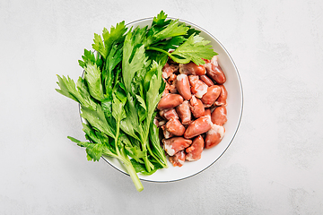 Image showing Fresh raw chicken hearts with celery leaves, reading for cooking