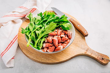 Image showing Fresh raw chicken hearts with celery leaves, reading for cooking