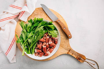 Image showing Fresh raw chicken hearts with celery leaves, reading for cooking