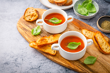 Image showing Homemade tomato soup with basil, toast and olive oil on a wooden