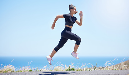 Image showing Runner woman, street and jump in nature with speed, fitness and energy for training, wellness and healthy by sea. Girl, running and fast on road for self care, exercise and workout by ocean in summer