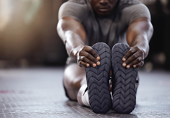 Image showing Stretching, feet and exercise with a man at gym for fitness, muscle and training workout. Athlete person with hands on shoes for warm up, goals and performance motivation on floor at a wellness club