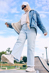 Image showing Balance, fashion or religion with a muslim woman outdoor in a cap and scarf for contemporary style. Islam, faith and hijab with a trendy young arab female person standing on one leg in modern clothes