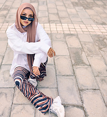 Image showing Portrait, fashion or city with a muslim woman outdoor in sunglasses and a scarf for urban style. Islam, religion or arabic and a trendy young saudi person sitting outside in modern clothes with space