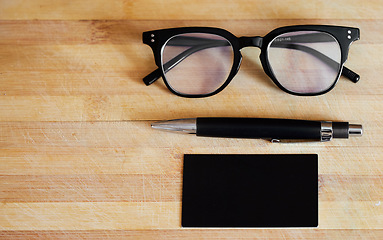 Image showing Glasses, pen and notebook on a desk in empty office for abstract background, business and vision. Eye sight, ideas and planner or journal on wooden table for reading and creative writing mockup space