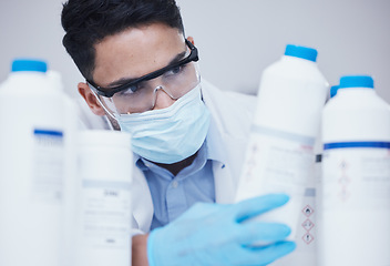 Image showing Container check, chemical bottle and man at scientist job with mask at pharmaceutical lab. Research, label reading and science of a male worker with manufacturing work and chemistry inventory