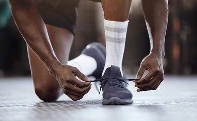 Image showing Tie, fitness and hands on shoes at gym for workout, training or exercise or runner ready to start exercising. Black man, goals and tie running shoes in sports performance, health practice or class