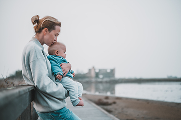 Image showing Tender woman caressing her little baby boy infant child outdoors on autumn trip to Secovlje salinas landscape park, Slovenia. Mother's unconditional love for her child.