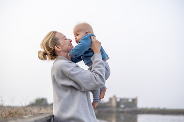 Image showing Tender woman caressing her little baby boy infant child outdoors on autumn trip to Secovlje salinas landscape park, Slovenia. Mother's unconditional love for her child.