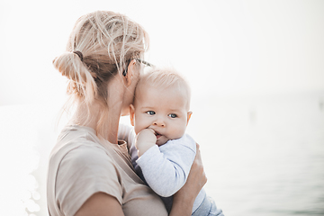 Image showing Tender woman caressing her little baby boy infant child outdoors. Mother's unconditional love for her child